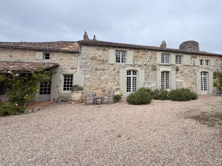 Stone château built around 1800: pale shutters, round tower, gravel courtyard