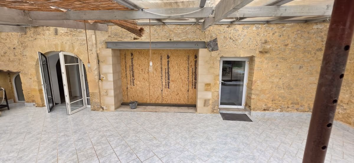 Mur en pierre avec ouverture provisoirement fermée sur une terrasse