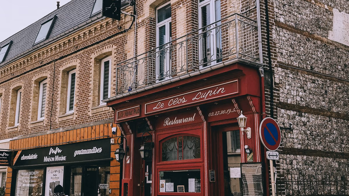 Devantures de commerces en rez-de-chaussée d'immeubles anciens de centre-ville, restaurant à l'angle et chocolaterie voisine