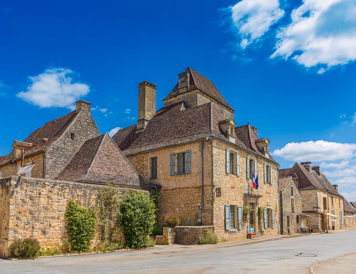 Maisons anciennes en pierre calcaire d'un village du Périgord, murs en moellons appareillés, encadrements en pierre de taille et toitures en tuiles