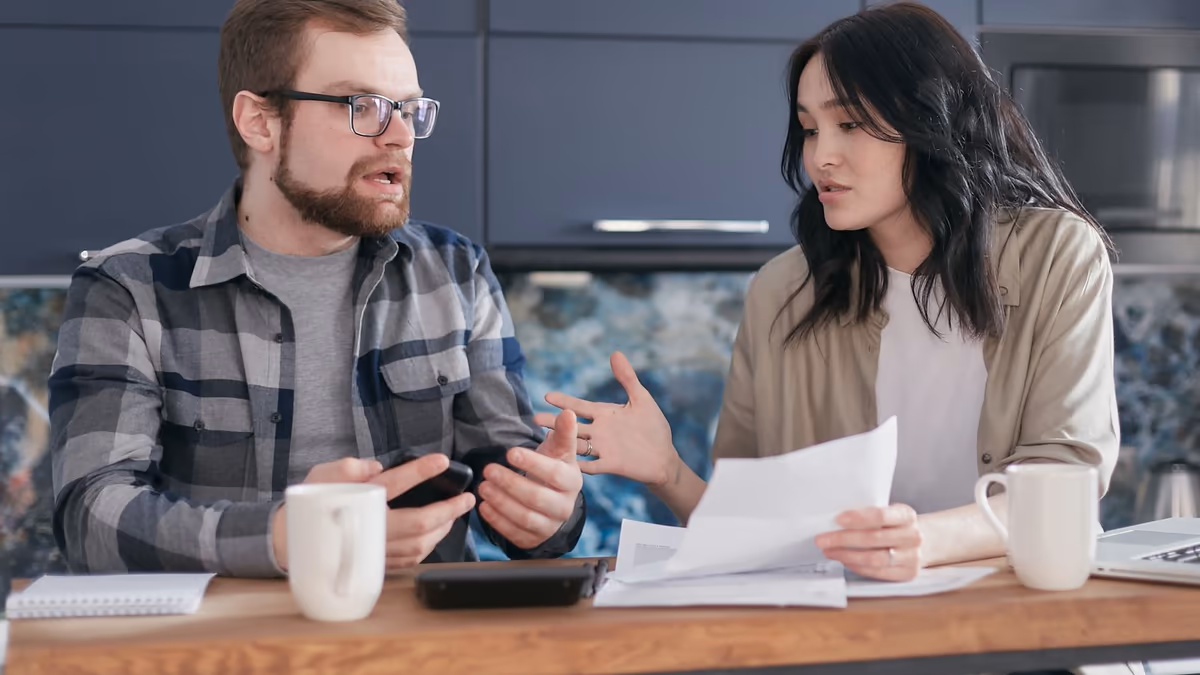 Deux personnes attablées relisant ensemble un document d'assurance après un sinistre, l'une tenant la feuille, l'autre commentant