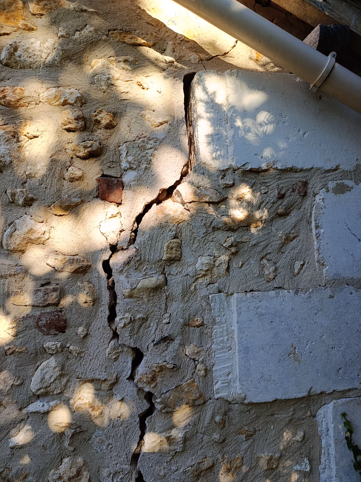 Open crack in a rubble stone wall, along a dressed stone