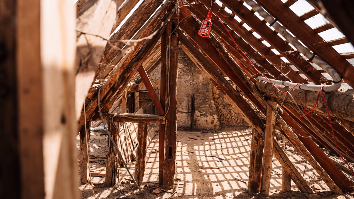 Comble non aménagé d'une maison ancienne, charpente et liteaux apparents sous la couverture avant travaux d'isolation