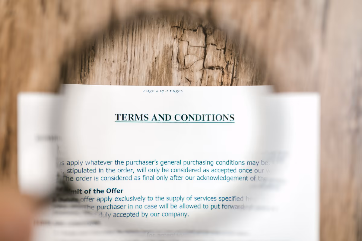 Page de conditions générales d'un contrat lue à la loupe, le titre du chapitre et un paragraphe agrandis sous la lentille