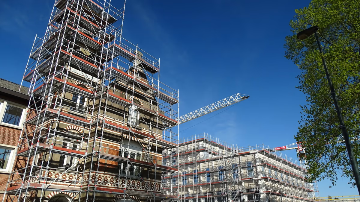 Immeubles d'habitation entièrement sous échafaudage pendant une campagne de travaux de façade, grue de chantier en arrière-plan