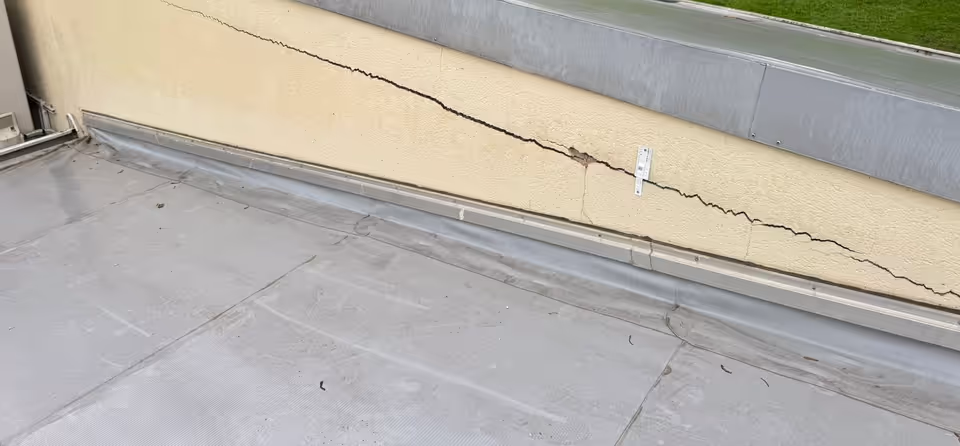 Longue fissure sur un acrotère au-dessus d'une toiture-terrasse