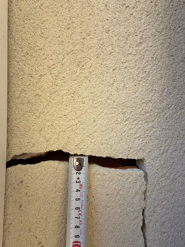 Ouverture d'une fissure d'enduit de façade mesurée au mètre ruban